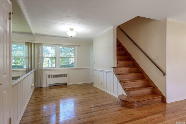 stairway featuring hardwood / wood-style floors, ornamental molding, a textured ceiling, and radiator