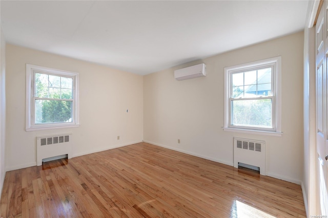 spare room featuring an AC wall unit, radiator, and a wealth of natural light