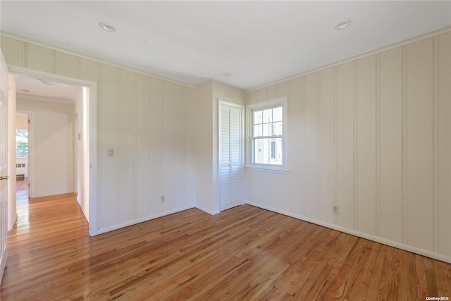 unfurnished room with ornamental molding, radiator heating unit, and light hardwood / wood-style flooring