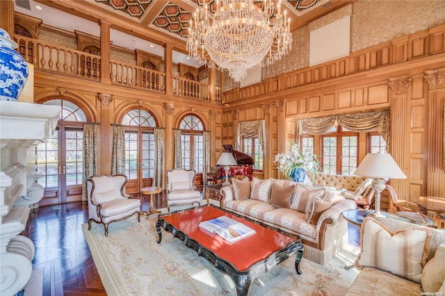 living room featuring a chandelier, a towering ceiling, a healthy amount of sunlight, and parquet flooring