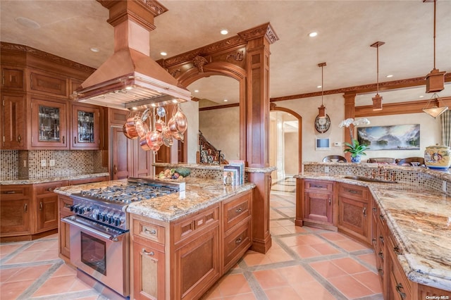 kitchen with high end stove, a kitchen island, decorative light fixtures, and premium range hood