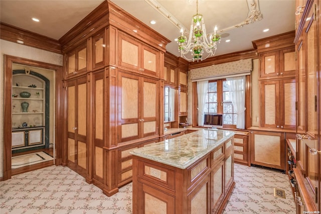 kitchen with a center island, light stone countertops, ornamental molding, decorative light fixtures, and a chandelier