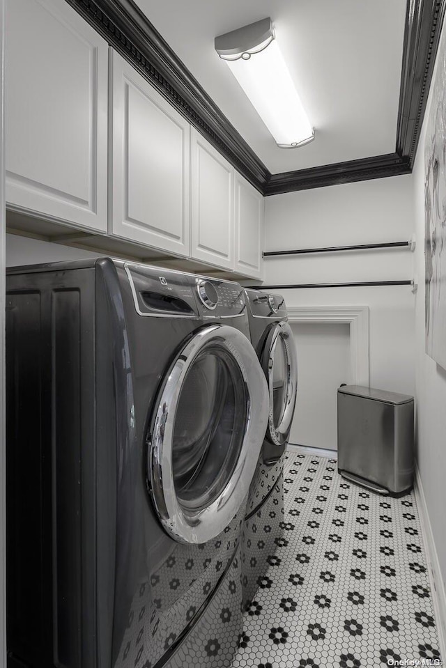 laundry area featuring washing machine and clothes dryer, crown molding, and cabinets