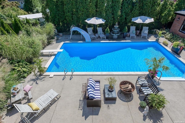 view of swimming pool with a diving board, a patio area, and a water slide