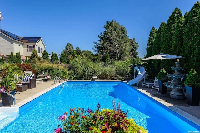 view of pool featuring a diving board, a patio area, and a water slide