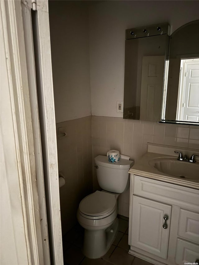 bathroom with tile patterned flooring, vanity, toilet, and tile walls