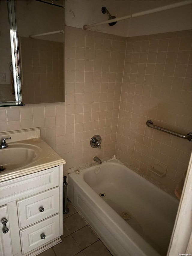 bathroom with tile patterned floors, tiled shower / bath combo, tile walls, and vanity