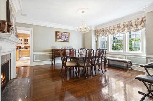 dining area featuring a high end fireplace, dark hardwood / wood-style flooring, an inviting chandelier, and ornamental molding