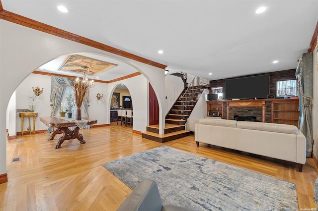 living room featuring crown molding, a fireplace, parquet floors, and a chandelier