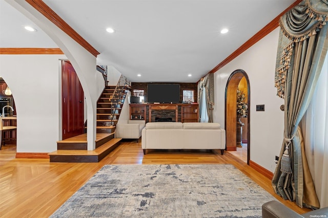 living room featuring a brick fireplace, light hardwood / wood-style flooring, and ornamental molding