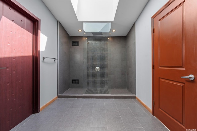 bathroom with a tile shower and a skylight