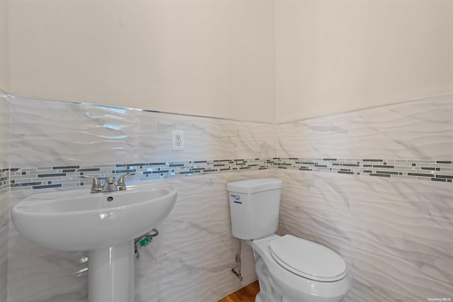 bathroom featuring toilet and tile walls