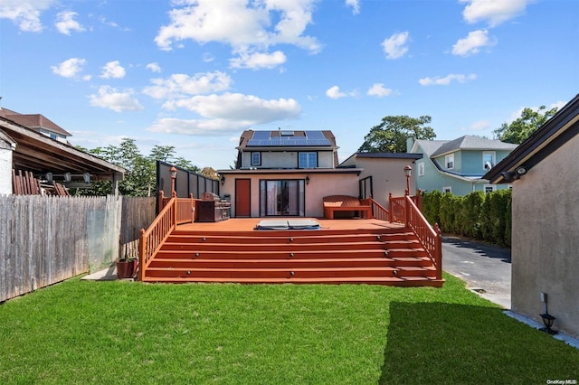 rear view of property featuring solar panels, a yard, and a wooden deck