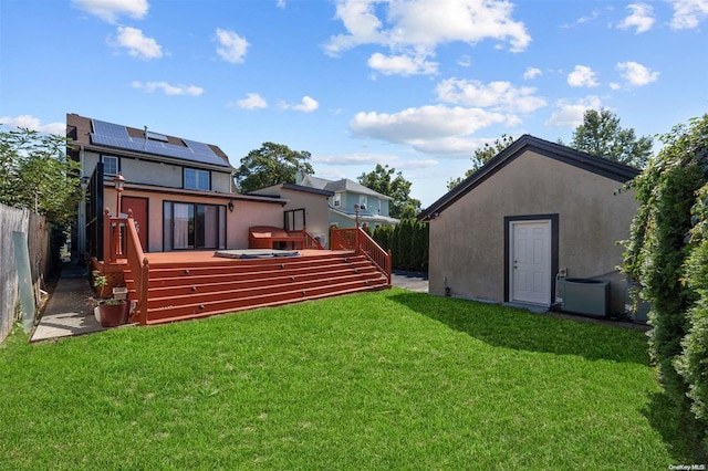 back of house with solar panels, central AC, a deck, and a lawn