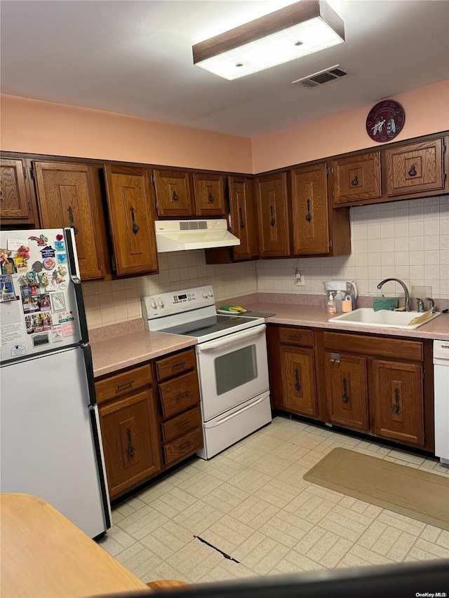 kitchen with white appliances, tasteful backsplash, and sink