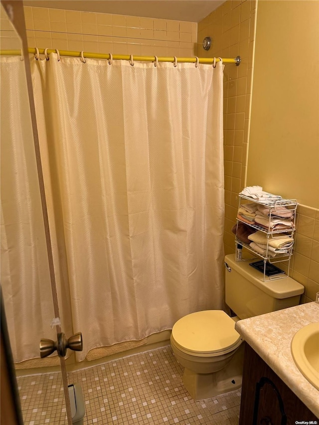 bathroom featuring tile patterned flooring, vanity, toilet, and tile walls