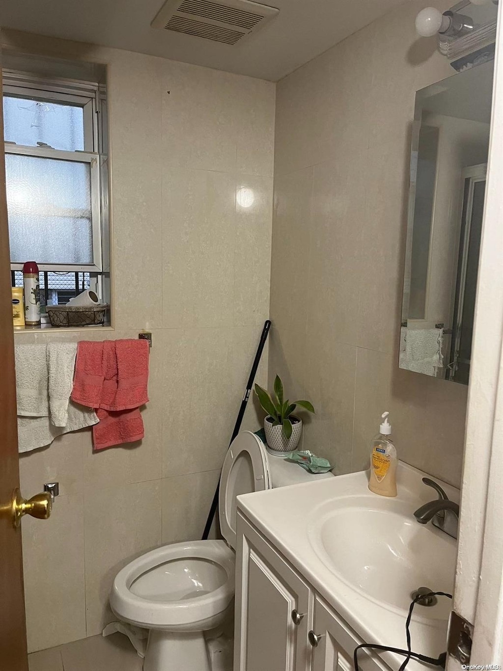 bathroom with tile patterned flooring, vanity, toilet, and tile walls