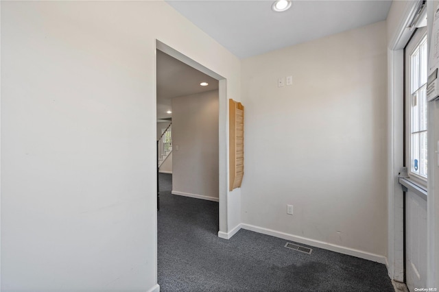 spare room featuring dark colored carpet and a wealth of natural light