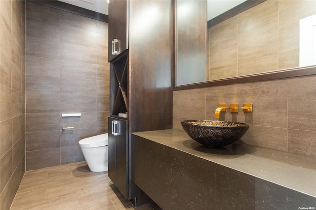 bathroom with sink, tile walls, and toilet