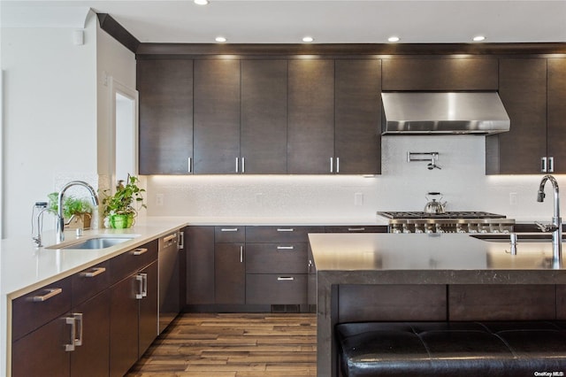 kitchen featuring dark brown cabinetry, wall chimney exhaust hood, and sink