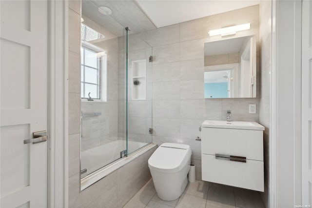 full bathroom featuring vanity, combined bath / shower with glass door, tile patterned flooring, toilet, and tile walls