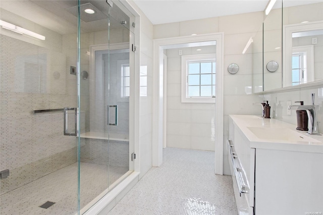 bathroom with vanity, a shower with shower door, and tile walls