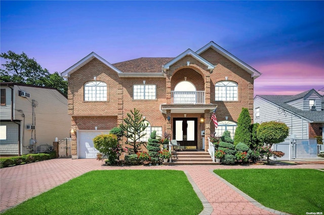 view of front of property featuring a lawn, a balcony, and a garage