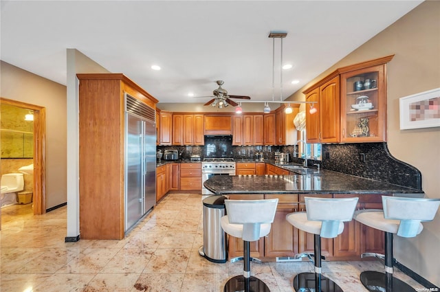 kitchen with decorative backsplash, premium appliances, decorative light fixtures, and a breakfast bar area