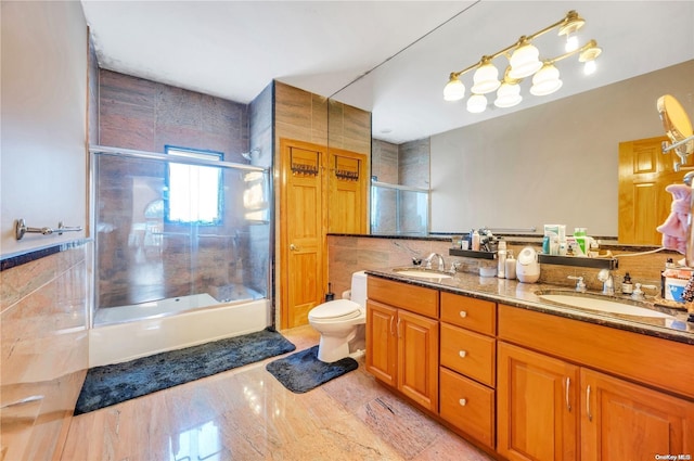 full bathroom with toilet, vanity, tile walls, and combined bath / shower with glass door