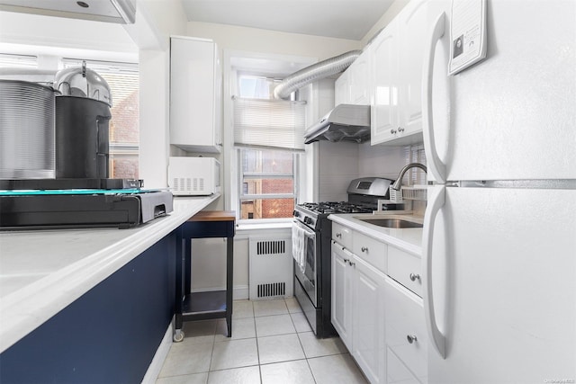 kitchen featuring white appliances, ventilation hood, light tile patterned floors, radiator heating unit, and white cabinetry