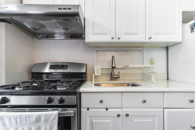 kitchen with white cabinets, sink, stainless steel gas range, decorative backsplash, and range hood