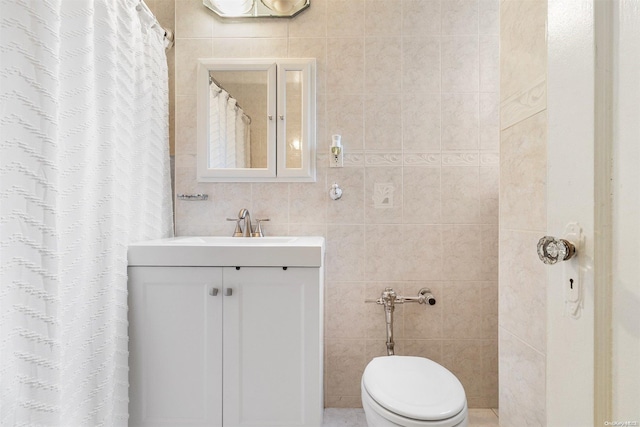 bathroom featuring vanity, toilet, and tile walls