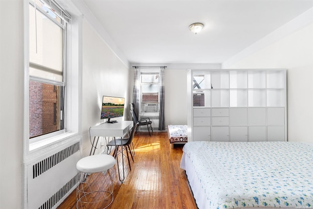 bedroom with radiator heating unit and wood-type flooring