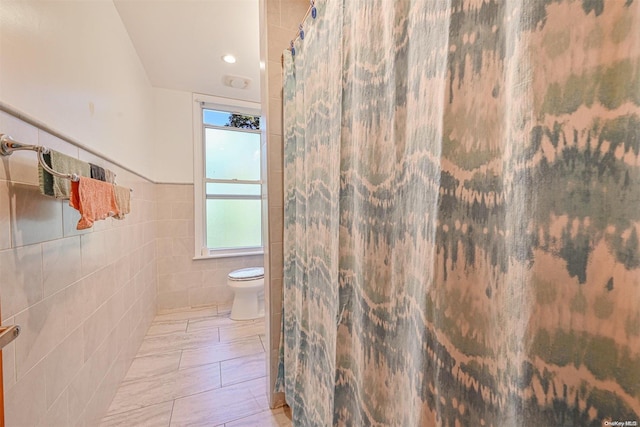 bathroom featuring toilet and tile walls