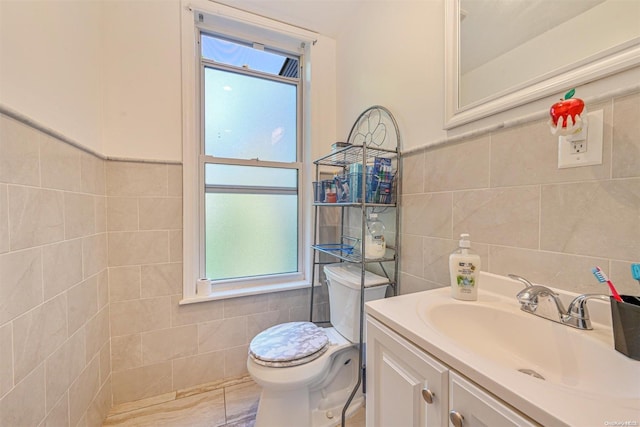 bathroom featuring vanity, toilet, and tile walls