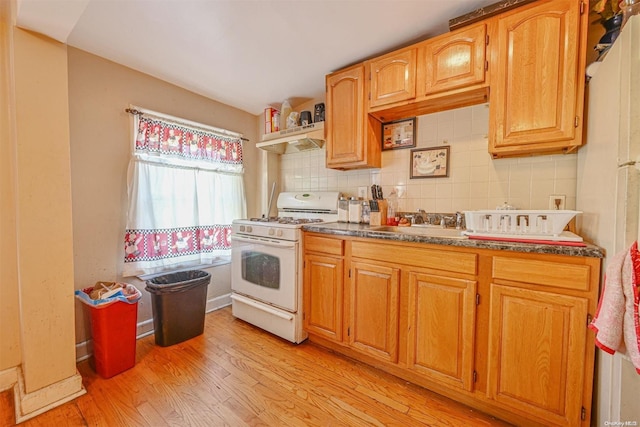 kitchen featuring backsplash, light hardwood / wood-style floors, white range with gas cooktop, and sink