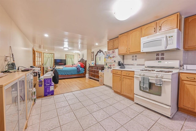 kitchen with tasteful backsplash, light brown cabinetry, light hardwood / wood-style floors, and white appliances