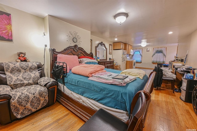 bedroom with white fridge and light wood-type flooring