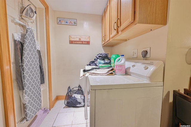 clothes washing area with cabinets, washing machine and dryer, and light tile patterned flooring