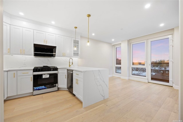 kitchen with white cabinets, appliances with stainless steel finishes, light hardwood / wood-style flooring, and pendant lighting