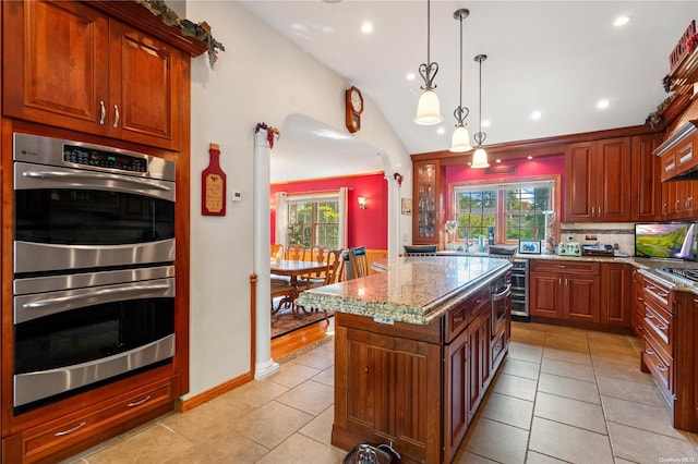 kitchen featuring pendant lighting, a center island, light stone countertops, decorative backsplash, and stainless steel double oven