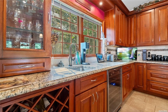 kitchen with light stone counters, beverage cooler, sink, and backsplash