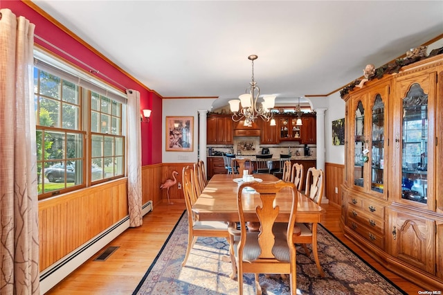 dining space featuring decorative columns, a baseboard radiator, a chandelier, and light hardwood / wood-style floors