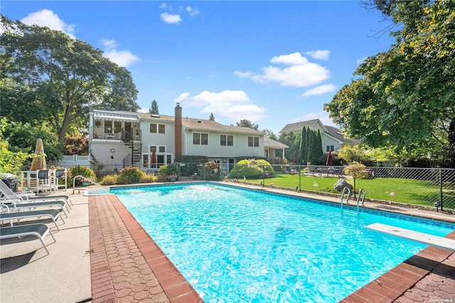 view of swimming pool with a patio area and a diving board