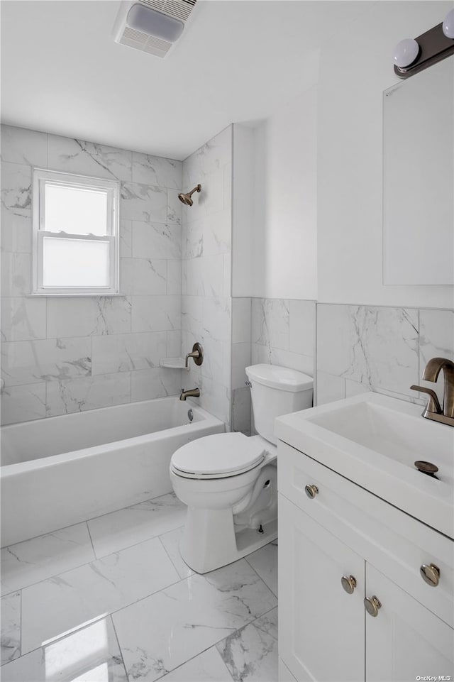 full bathroom with tile walls, vanity, tiled shower / bath combo, and toilet