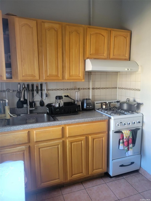 kitchen featuring tasteful backsplash, white gas range, sink, and light tile patterned floors