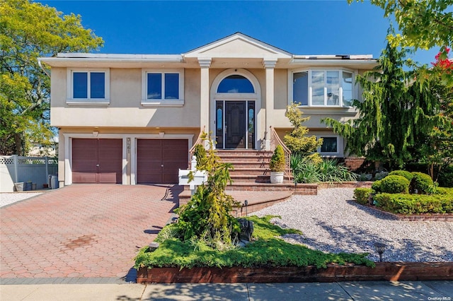 3461 Ocean Ave, Oceanside, NY 11572 - bi-level home featuring stucco siding, an attached garage, and decorative driveway
