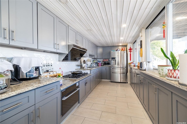 3461 Ocean Ave, Oceanside, NY 11572 - kitchen featuring stainless steel appliances, gray cabinets, light stone countertops, tasteful backsplash, and light tile patterned flooring