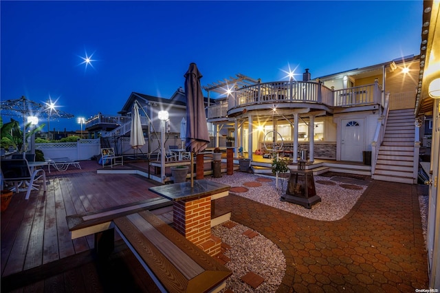 3461 Ocean Ave, Oceanside, NY 11572 - back of house at night with a wooden deck, stairs, a patio, and a balcony