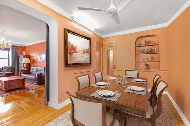 dining room with ceiling fan with notable chandelier, hardwood / wood-style flooring, and crown molding